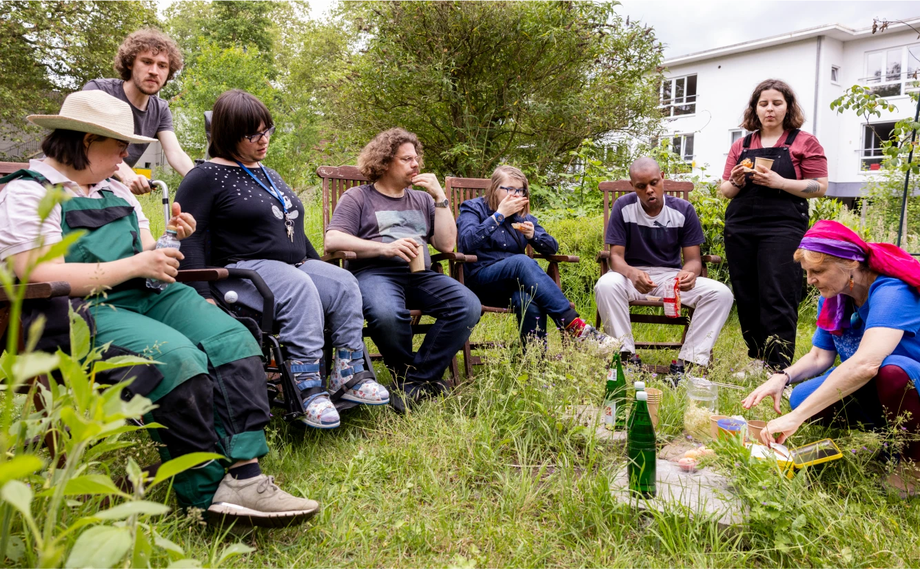 Eine Personengruppe sitzt im Garten.