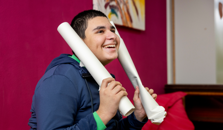 teaserbild_kinder Ein lächelnder Junge hält zwei Papierrollen in den Händen.