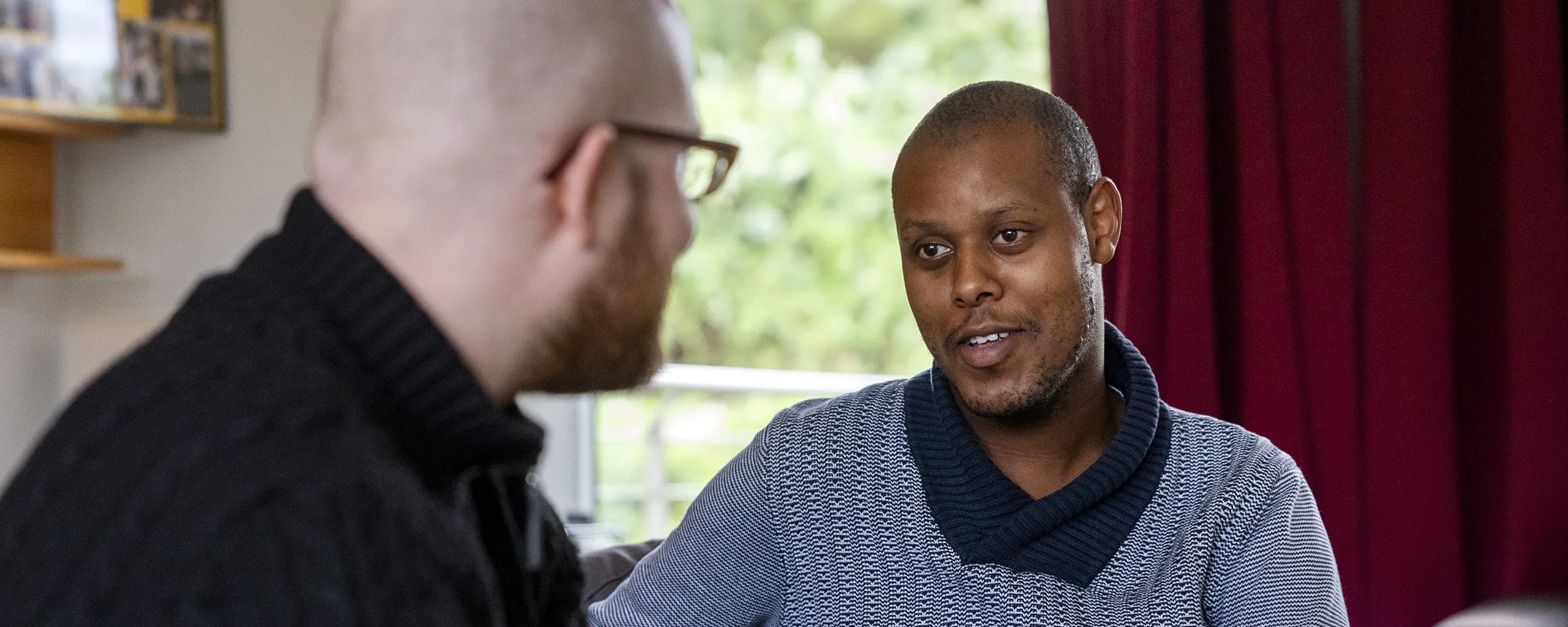 Zwei Männer sitzen nebeneinander und unterhalten sich.